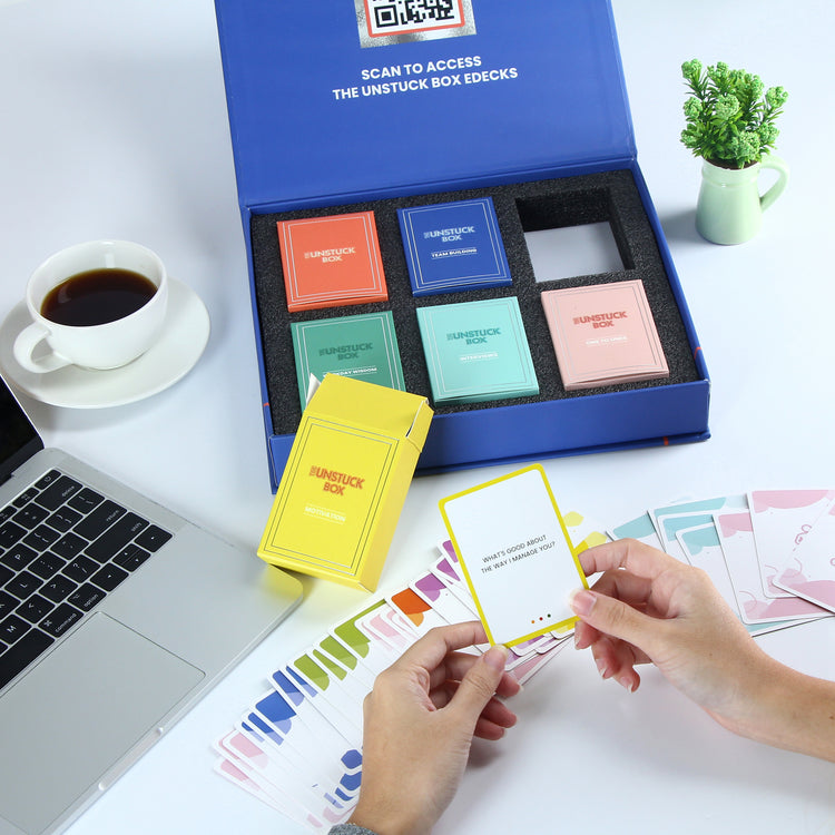 Person holding a card from The Unstuck Box for Teams, a productivity tool featuring curated card decks and eDeck access for enhancing teamwork and creativity.