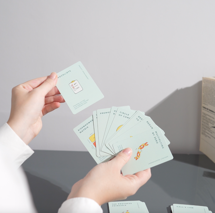 Person holding The Unstuck Box deck, featuring 48 idea cards for strategic thinking, problem-solving, decision-making, project management, and leadership.