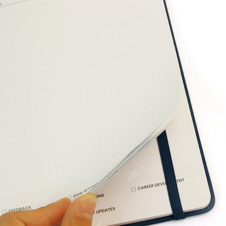 Close-up of a planner with a hand holding it open on a white background